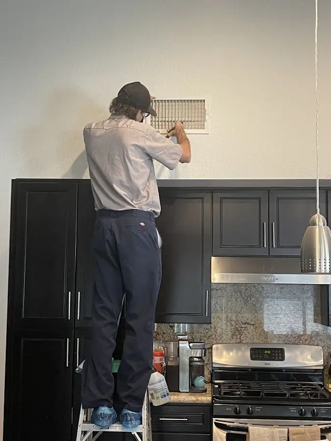 Technician inspecting an air vent during HVAC service in Robinson